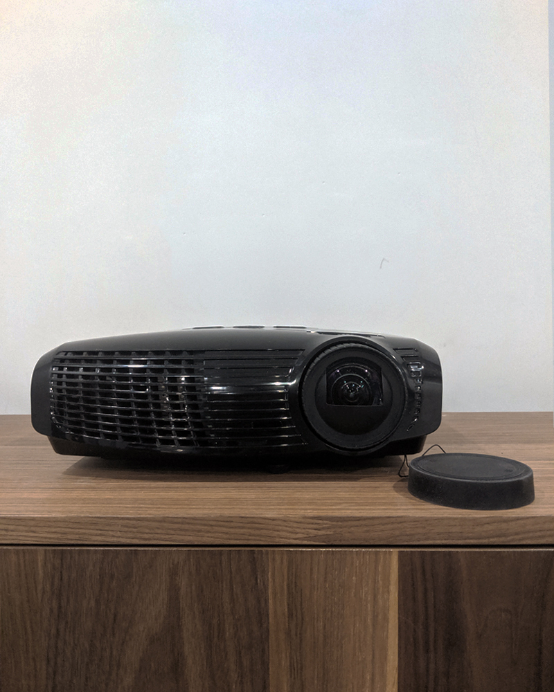 Black projector on wood table.